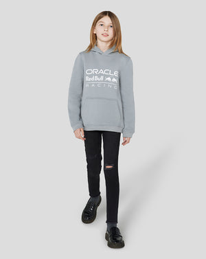 Girl wearing a light grey Oracle Red Bull Racing Junior Core Overhead Hoodie with a white logo across the chest