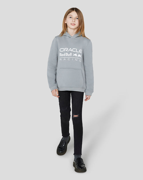 Girl wearing a light grey Oracle Red Bull Racing Junior Core Overhead Hoodie with a white logo across the chest