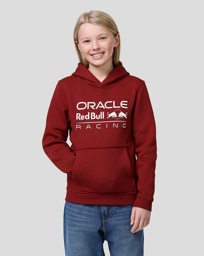 Smiling girl wearing a maroon Oracle Red Bull Racing hoodie with a white chest logo.