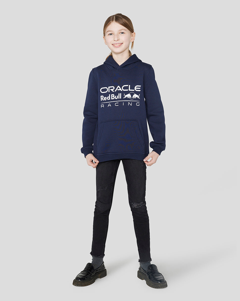 Girl wearing a Night Sky Oracle Red Bull Racing hoodie with a large logo and hands in pockets