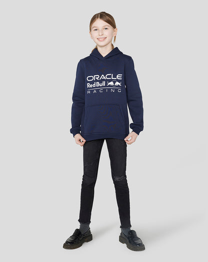 Girl wearing a Night Sky Oracle Red Bull Racing hoodie with a large logo and hands in pockets
