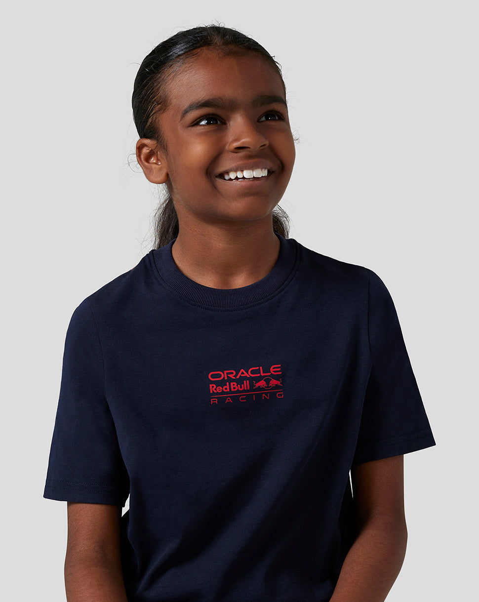 Close up of a smiling child wearing a navy T shirt with a red Oracle Red Bull Racing logo on the chest