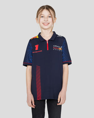 Front view of a smiling girl wearing a navy Oracle Red Bull Racing junior polo with Verstappen branding