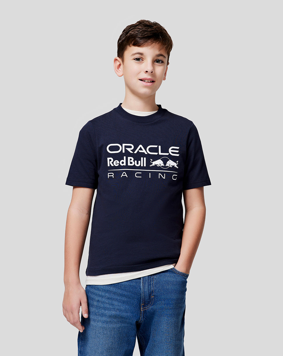 Front view of a smiling boy wearing a navy Red Bull Racing Junior Large Front Logo T Shirt with a bold front logo