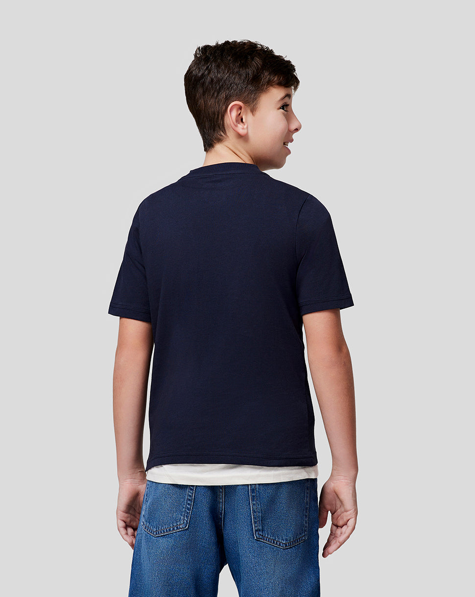 Back view of a boy wearing a navy Red Bull Racing T shirt with a white long sleeve underneath