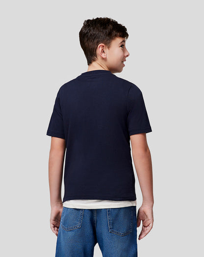 Back view of a boy wearing a navy Red Bull Racing T shirt with a white long sleeve underneath