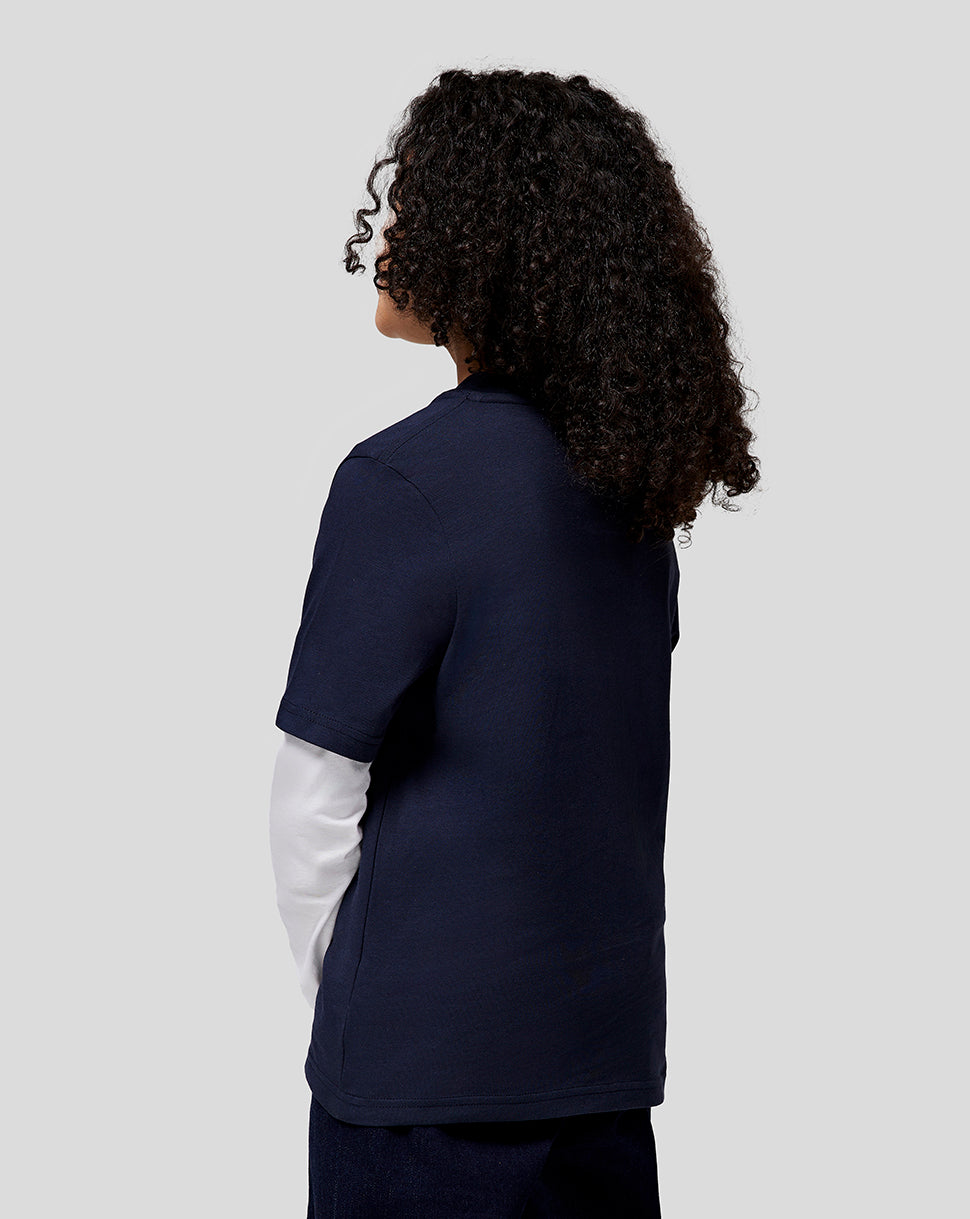Back view of a young person in a navy Red Bull Racing Junior Large Front Logo T Shirt with a white sleeve underneath