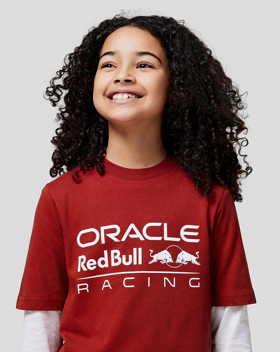 Young girl wearing a red Oracle Red Bull Racing juniors T shirt with a bold white logo on the chest