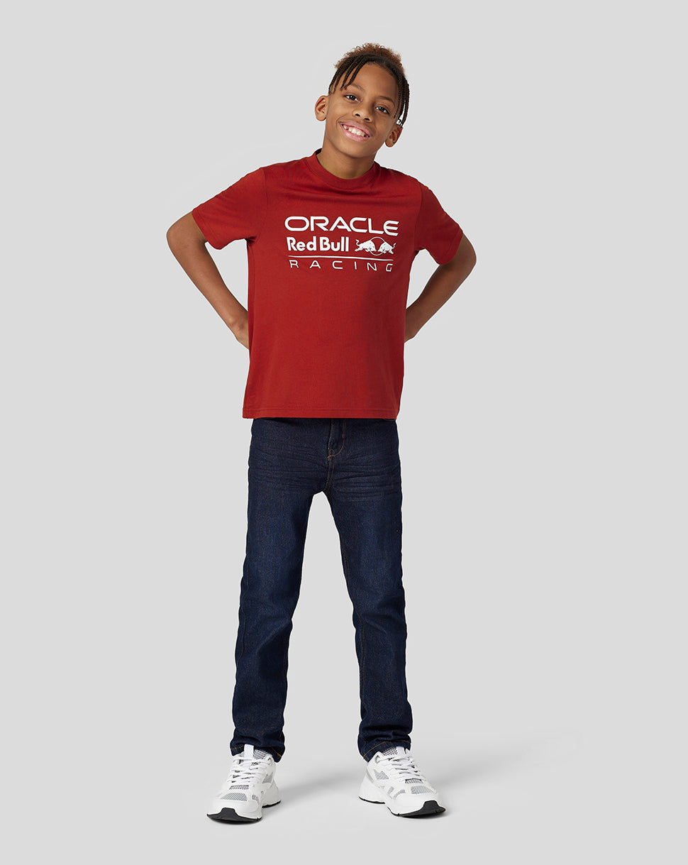 Front view of a child wearing a red Oracle Red Bull Racing juniors T shirt with large white logo on the chest