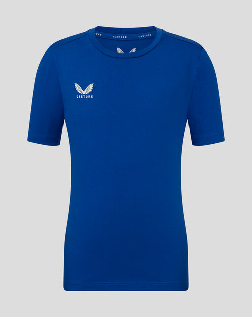 Front view of blue Junior Cotton Leisure Tee with Castore logo on the left chest and branding along the inside neck.