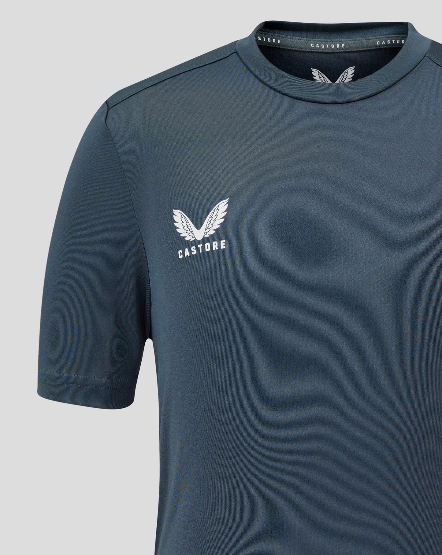 Dark slate junior performance tee with crew neck and short sleeves showing a white Castore wing logo on the chest.