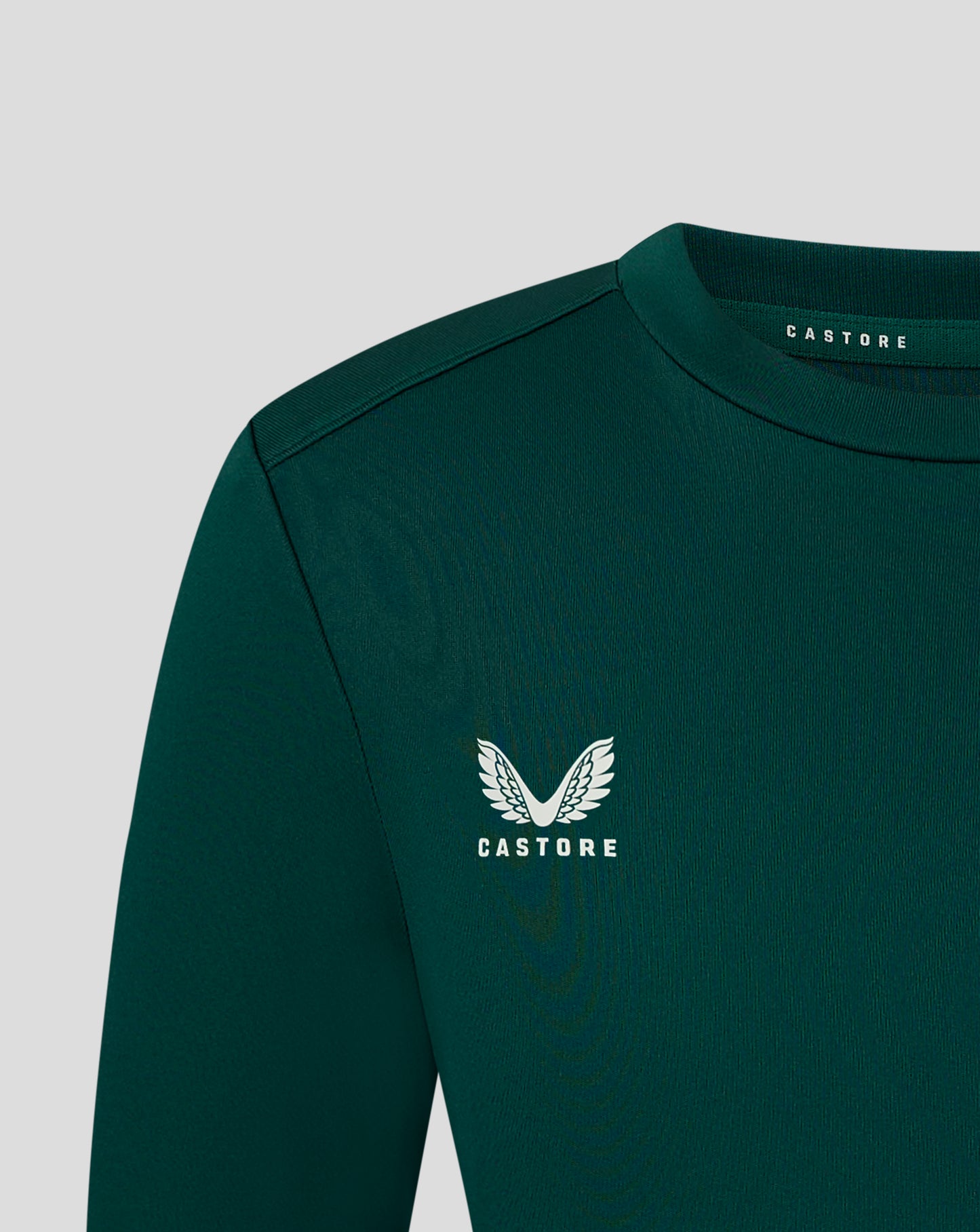 Shoulder and neck close up of dark green junior performance tee with forward shoulder seam and Castore branding