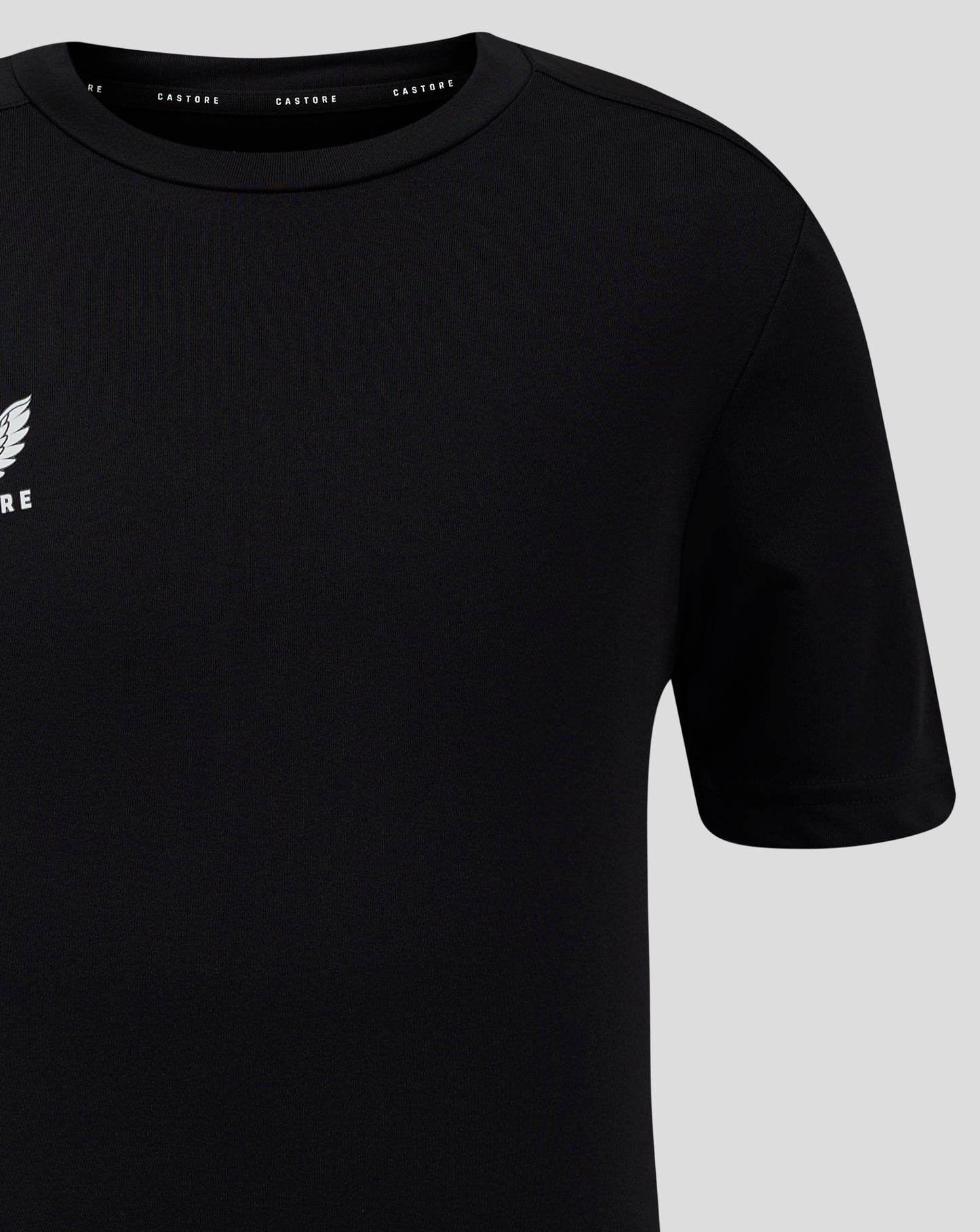 Close up of black Junior Performance Tee showing crew neck collar and partial white Castore logo on the left chest