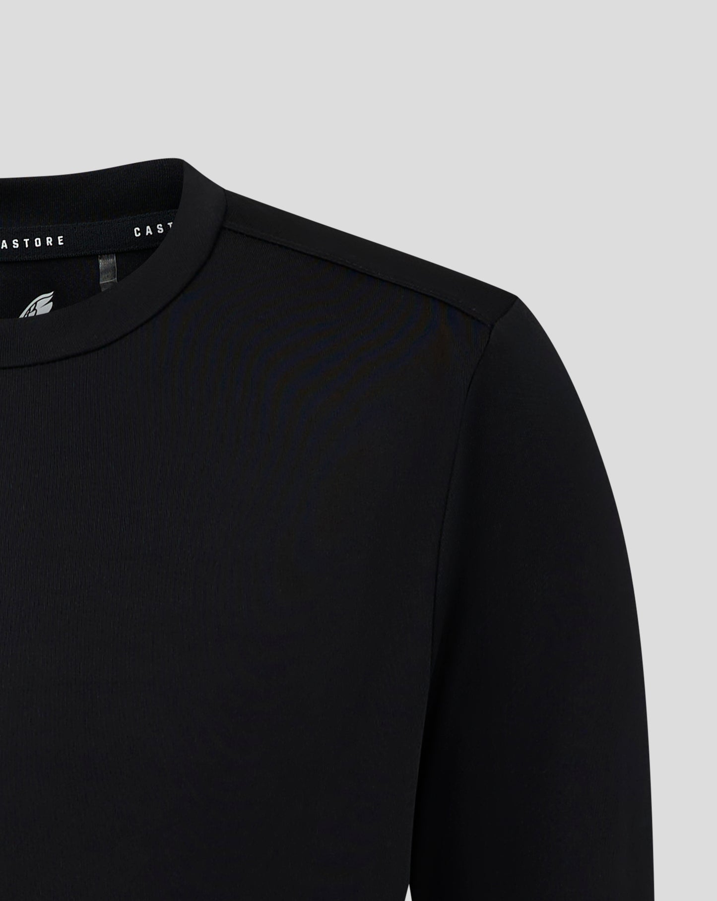 Front close-up of black junior long sleeve tee with white Castore crest on left chest