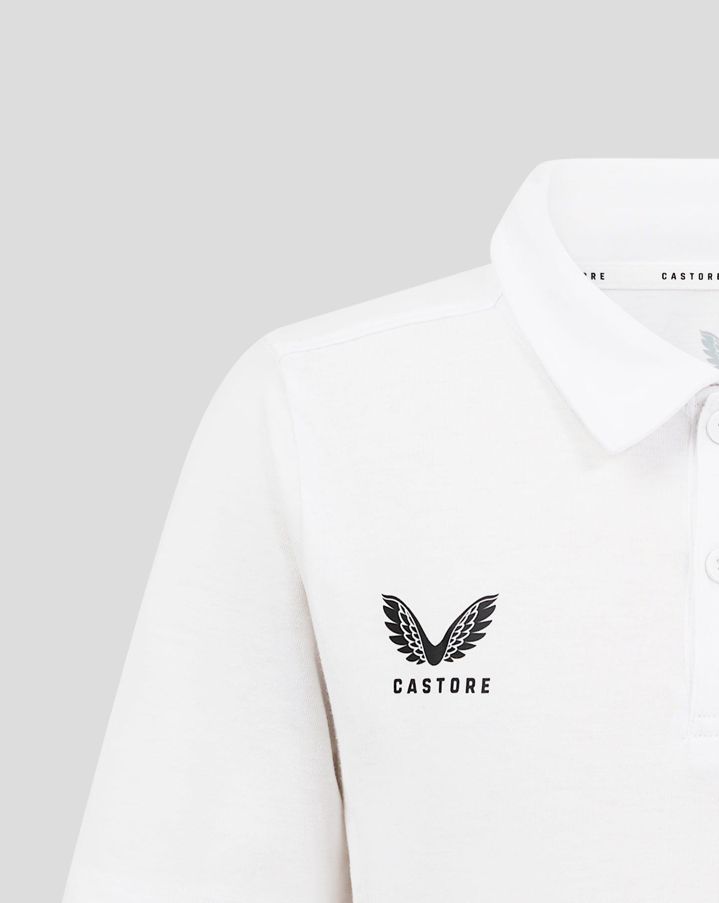 Close-up of the white polo showing the large Castore wing logo on the chest