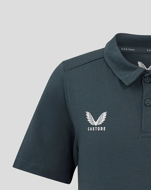 Close-up of the dark slate junior polo showing the white crest on the left chest and collar details