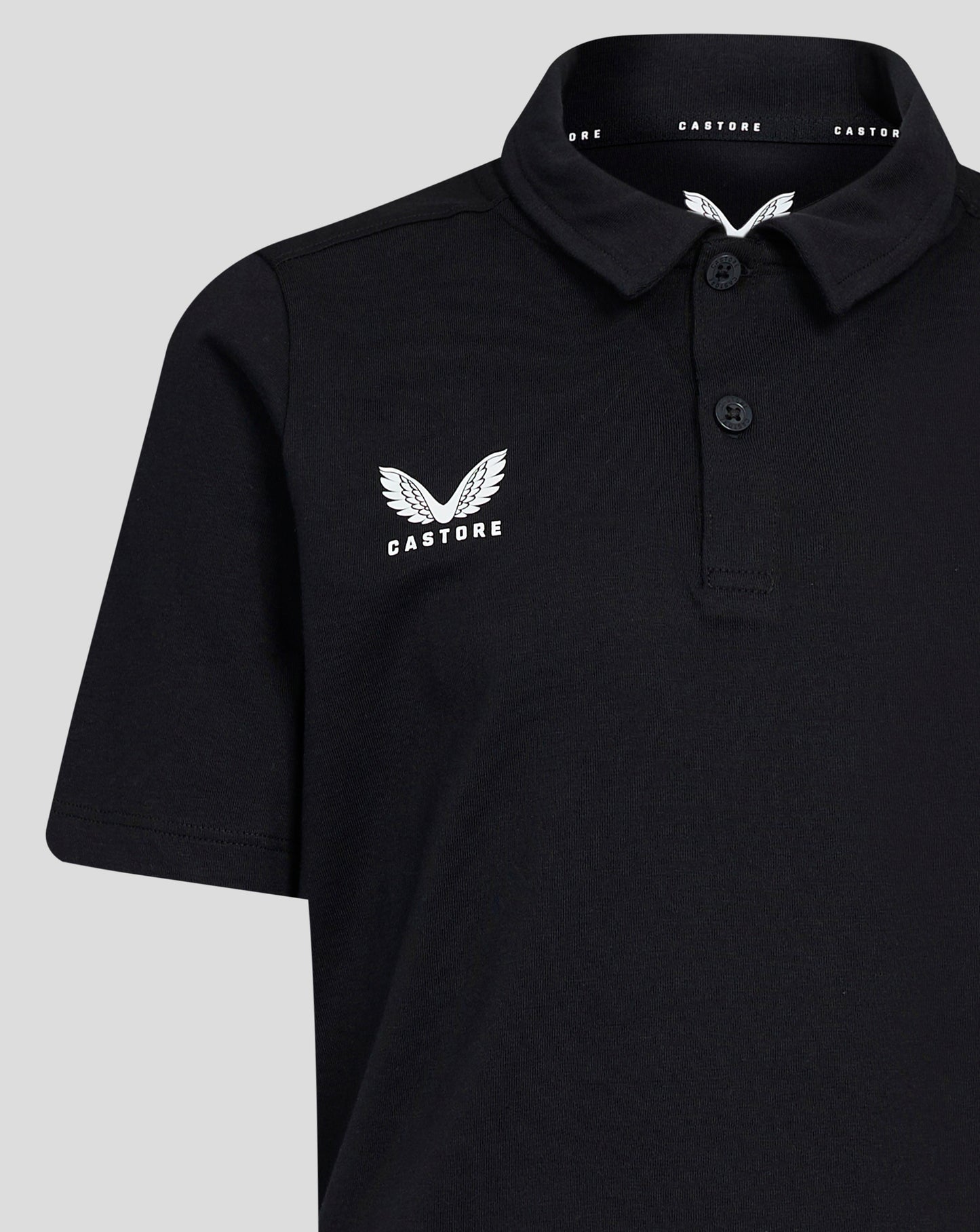 Front view of black Junior Cotton Leisure Polo with self fabric collar three button placket and Castore wing logo on left chest