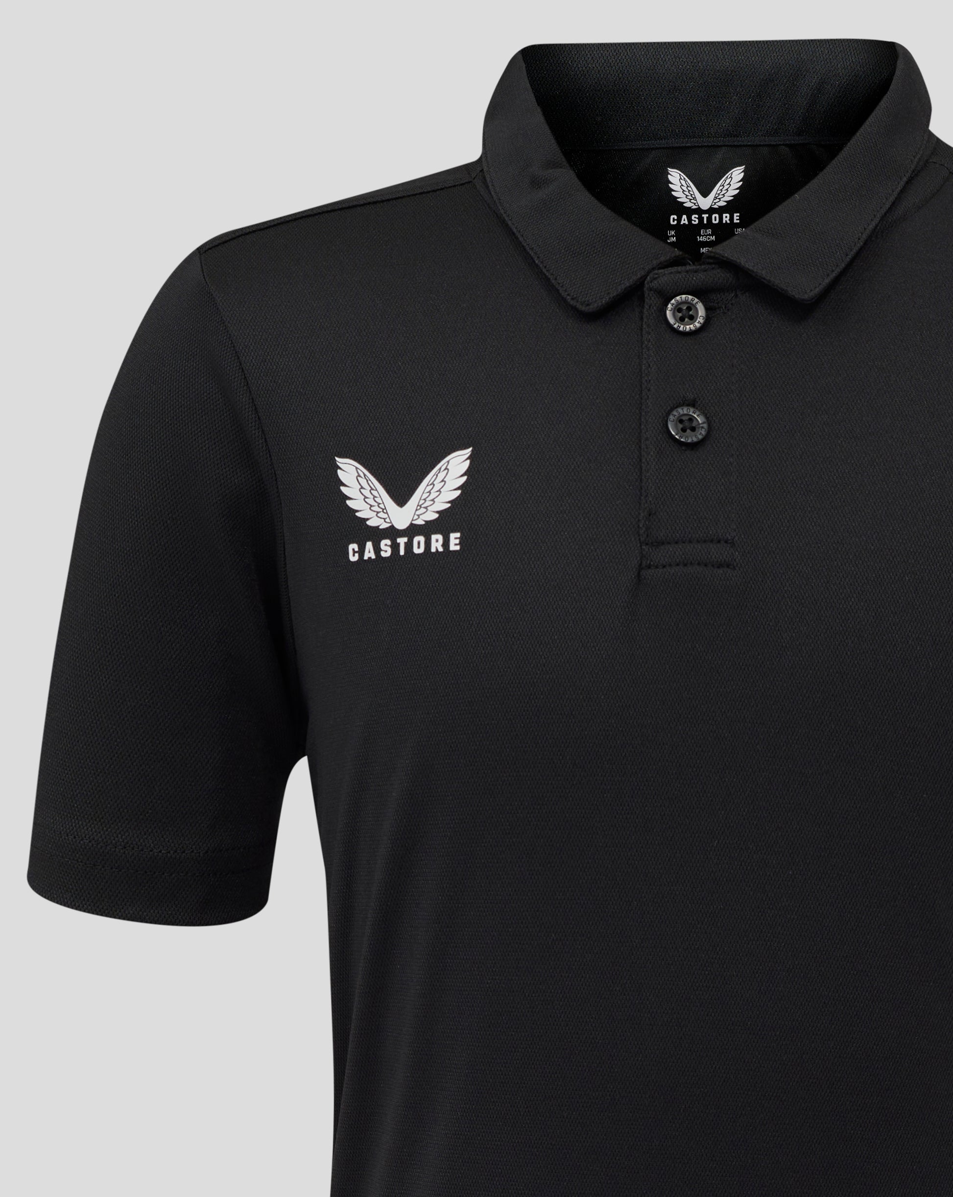 Close-up of black Junior Performance Polo with white Castore wing logo on the left chest and visible collar edge