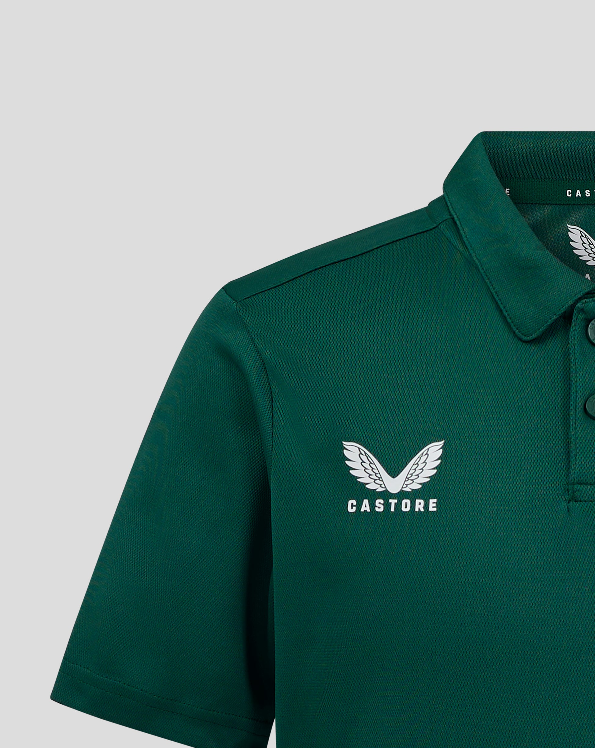 Front view of dark green junior polo with large white Castore wings logo and CASTORE text on the chest