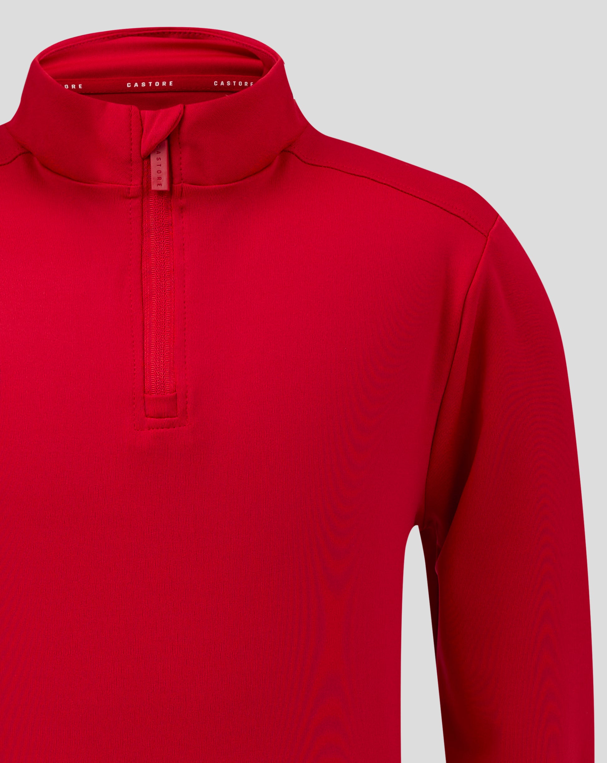 Close up of red junior quarter zip showing funnel neck and zipper with chin guard and Castore branding inside