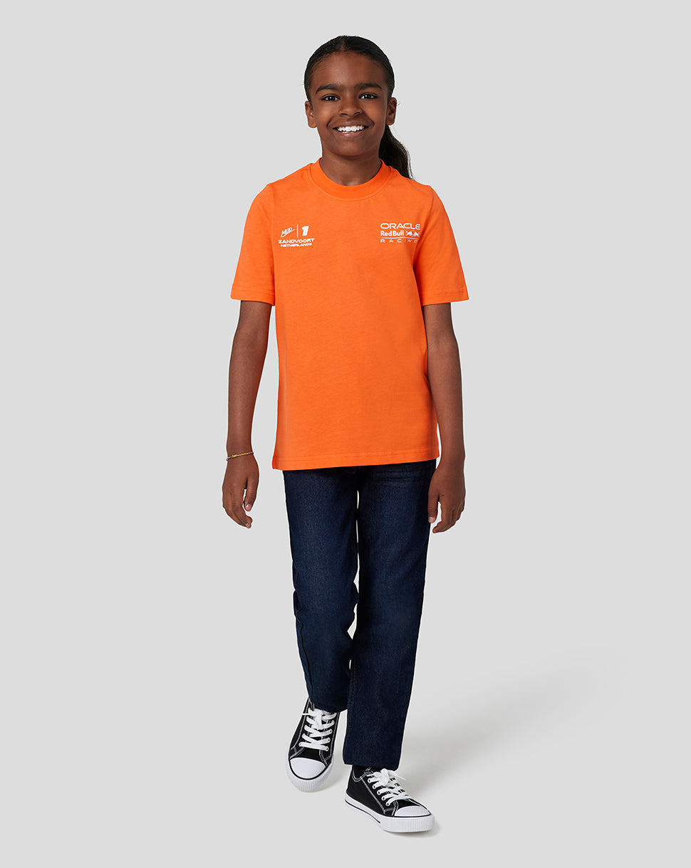 Front view of a smiling child wearing the orange Oracle Red Bull Racing junior T shirt with Zandvoort Netherlands and Oracle Red Bull Racing logos on the chest.