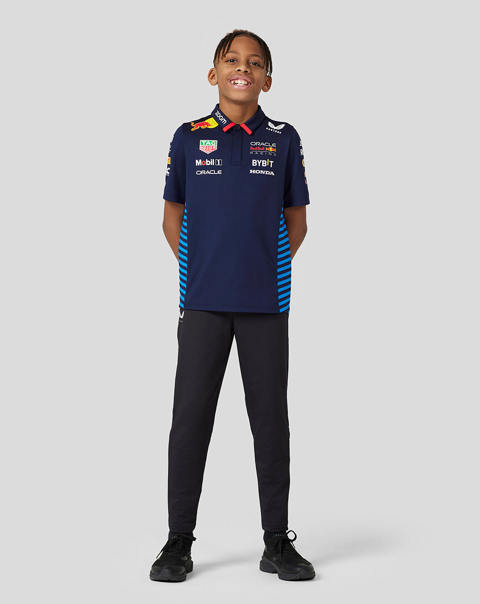 Front view of a smiling child in a navy Teamline polo with sponsor logos and blue striped side panels