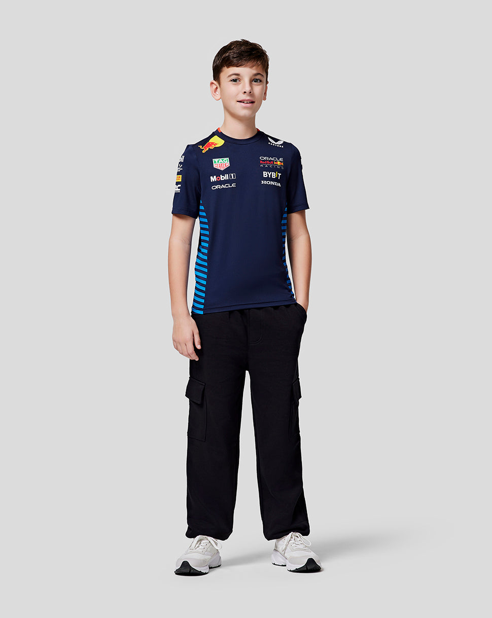 Boy in navy Oracle Red Bull Racing Set Up Tee with blue side stripes black cargo pants and white sneakers