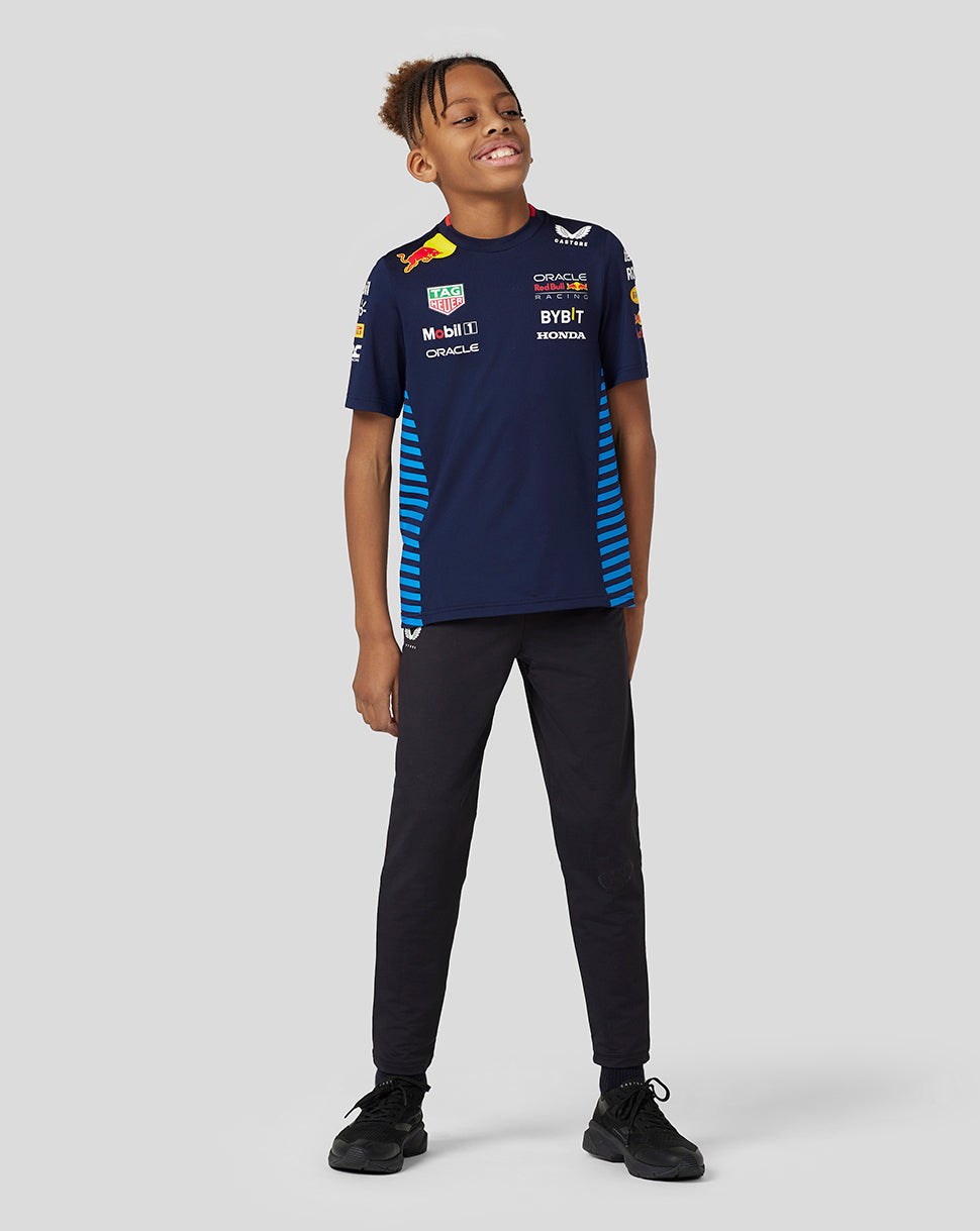 Front view of a young model wearing navy Night Sky Set Up Tee with blue striped side panels and multiple sponsor logos.