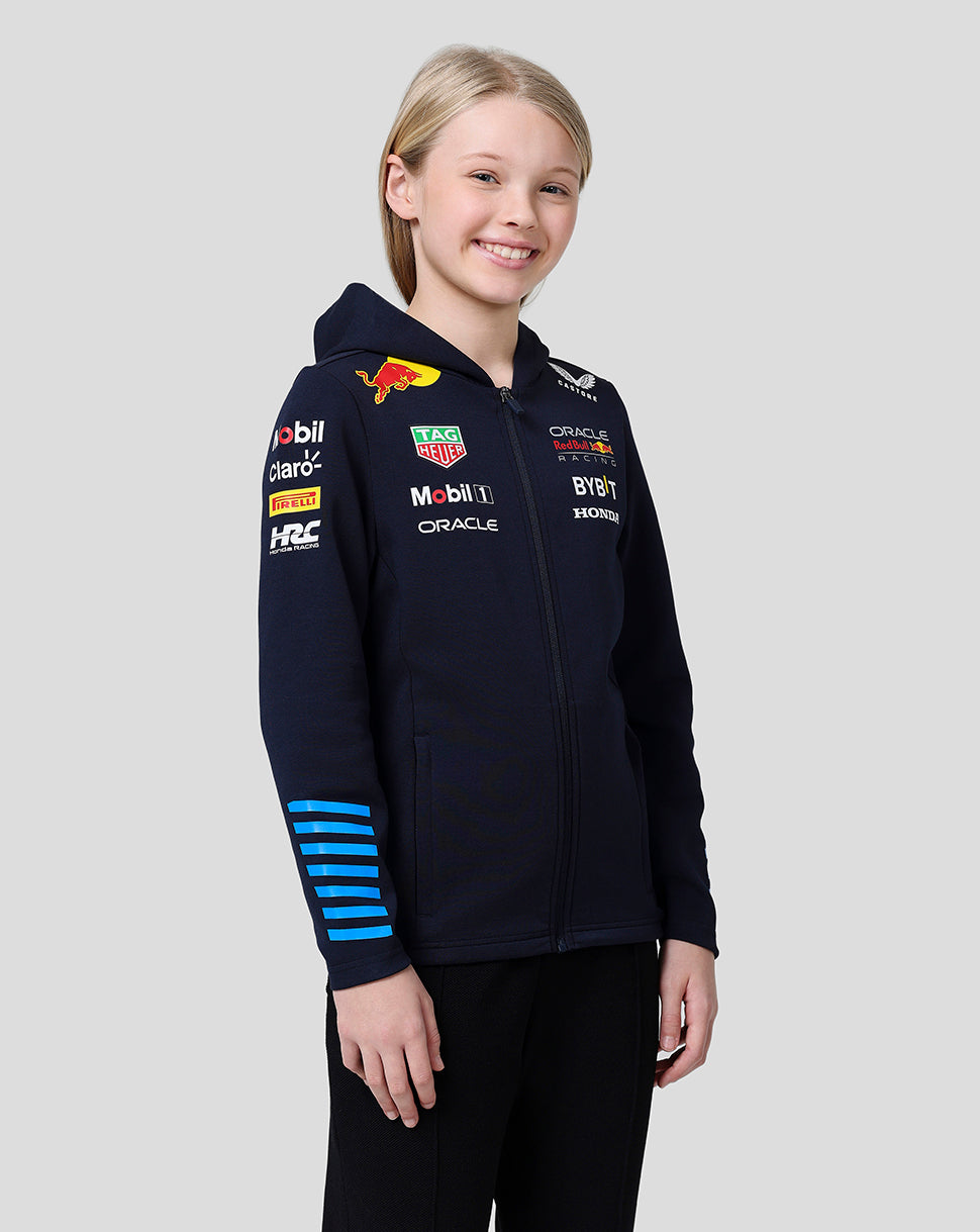 Smiling girl wearing navy Oracle Red Bull Racing Junior Teamline full zip hoodie with sponsor logos on chest and sleeve