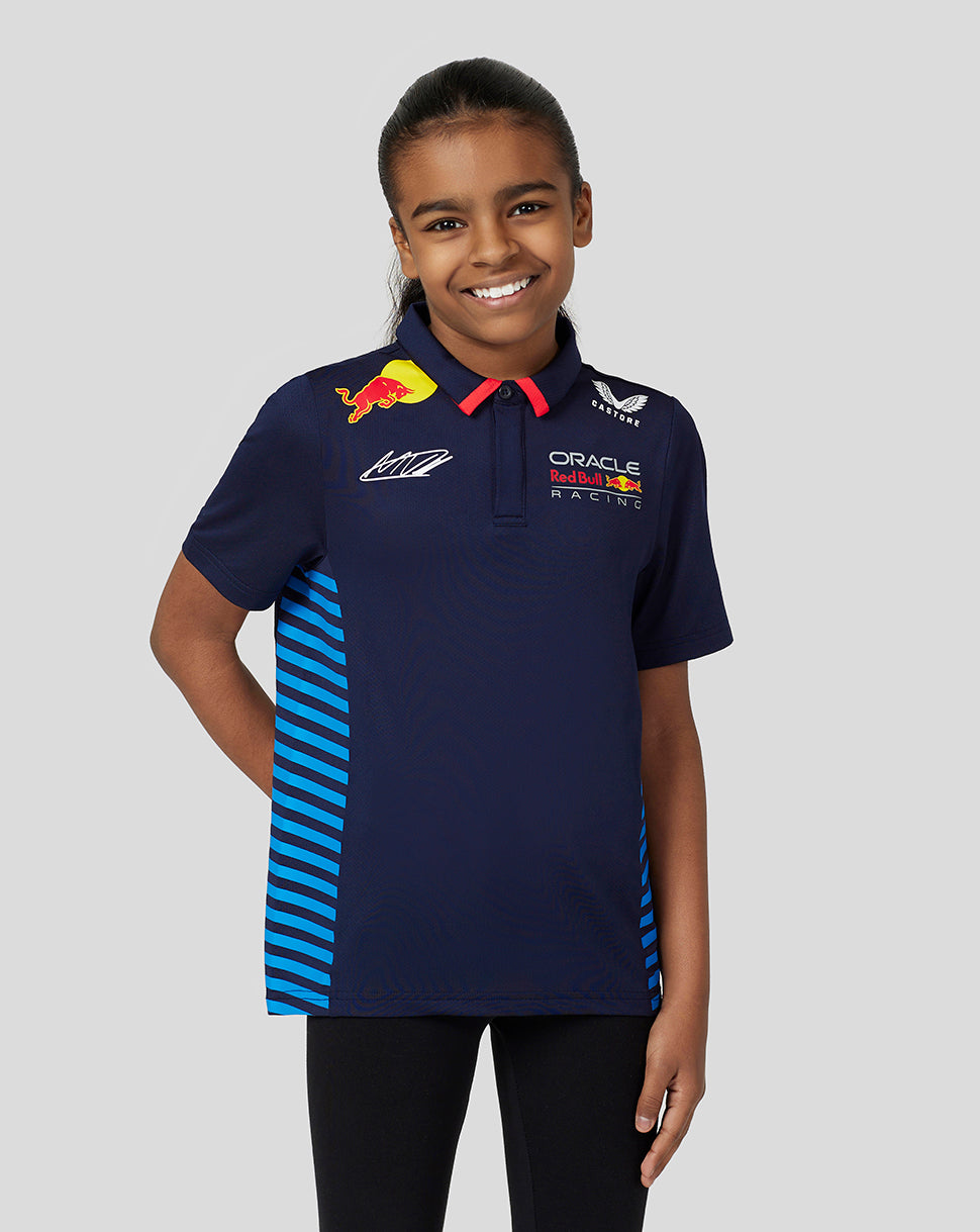 Smiling girl in navy Verstappen junior polo with blue side stripes and team logos on the chest.