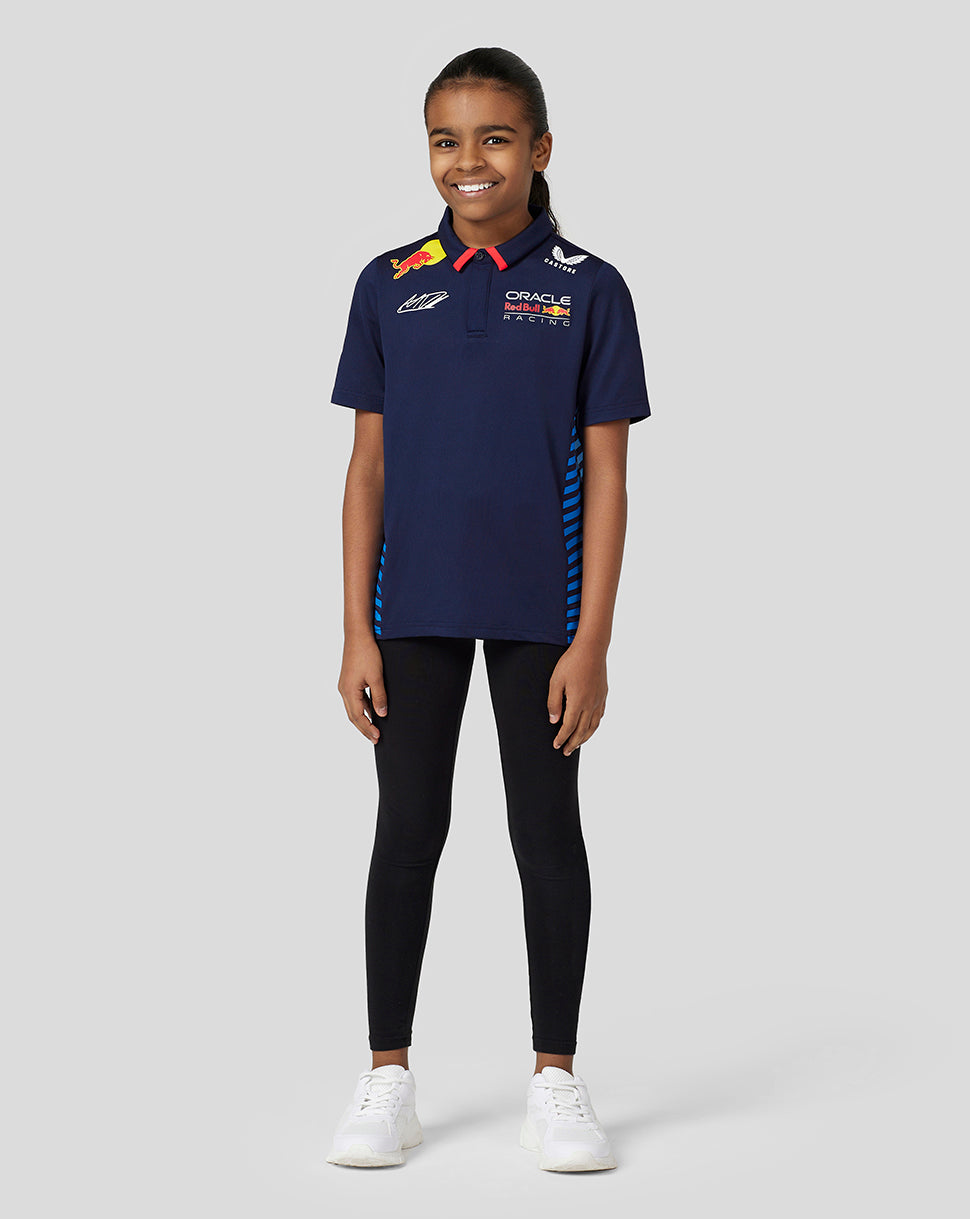 Full body shot of a girl in a navy Verstappen Teamline polo with blue striped side panels and racing logos on chest