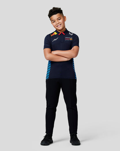 Young model wearing Oracle Red Bull Racing junior teamline polo in Night Sky with blue side panels, arms crossed.