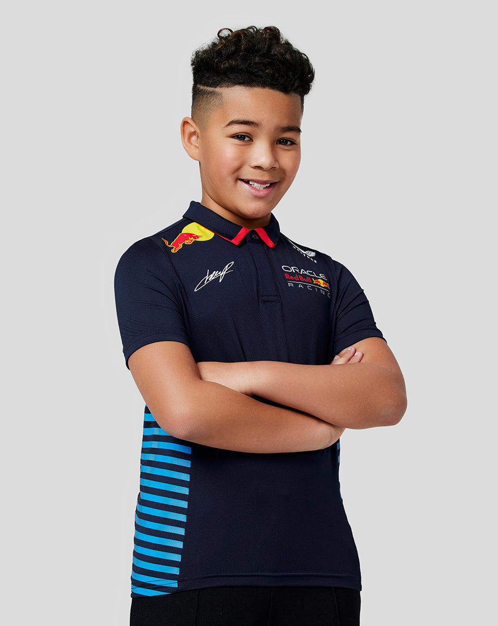 Smiling boy in navy Oracle Red Bull Racing junior teamline polo with blue stripe side panels.