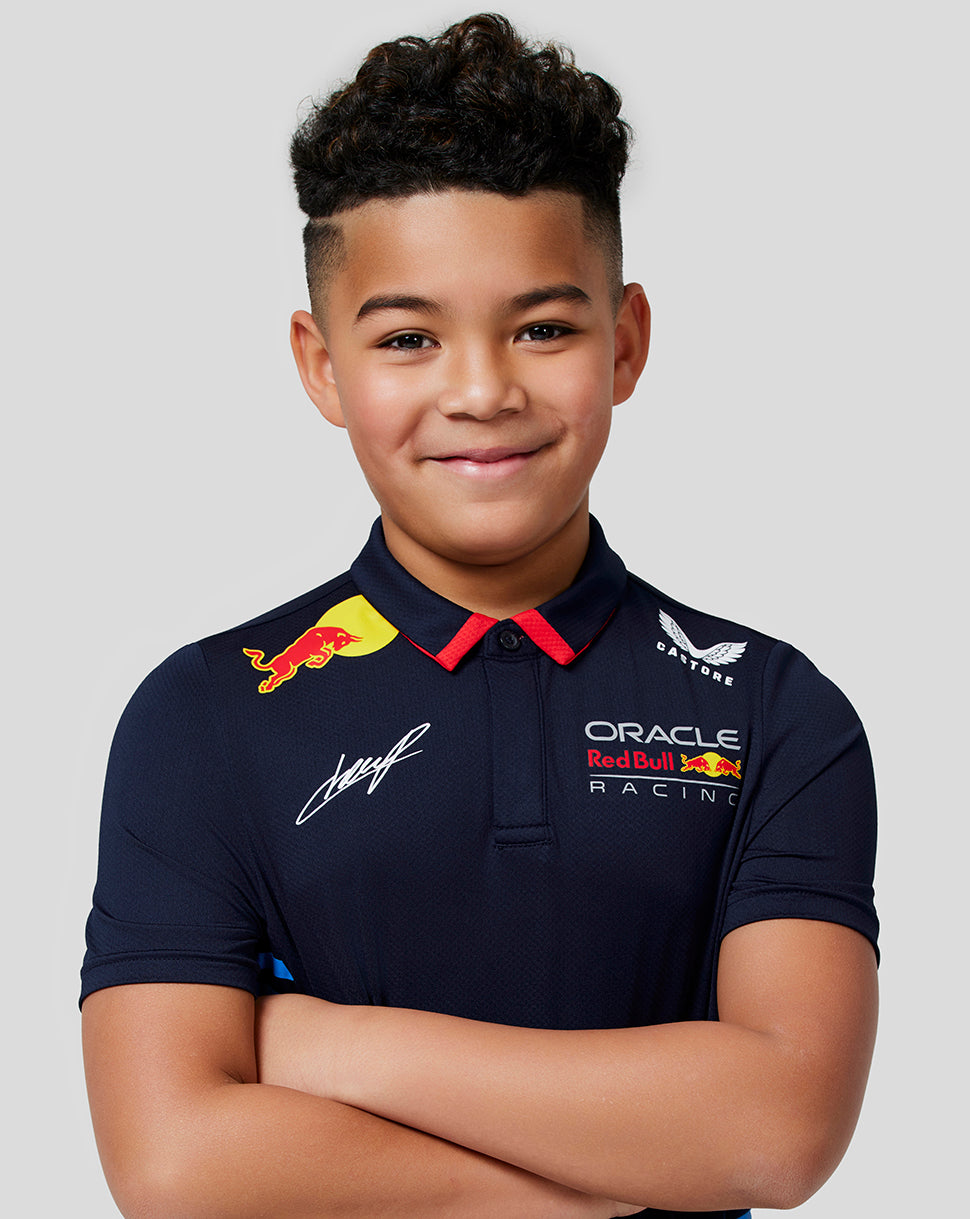 Close up of smiling boy in navy teamline polo showing Oracle Red Bull Racing chest logo and blue striped panels.