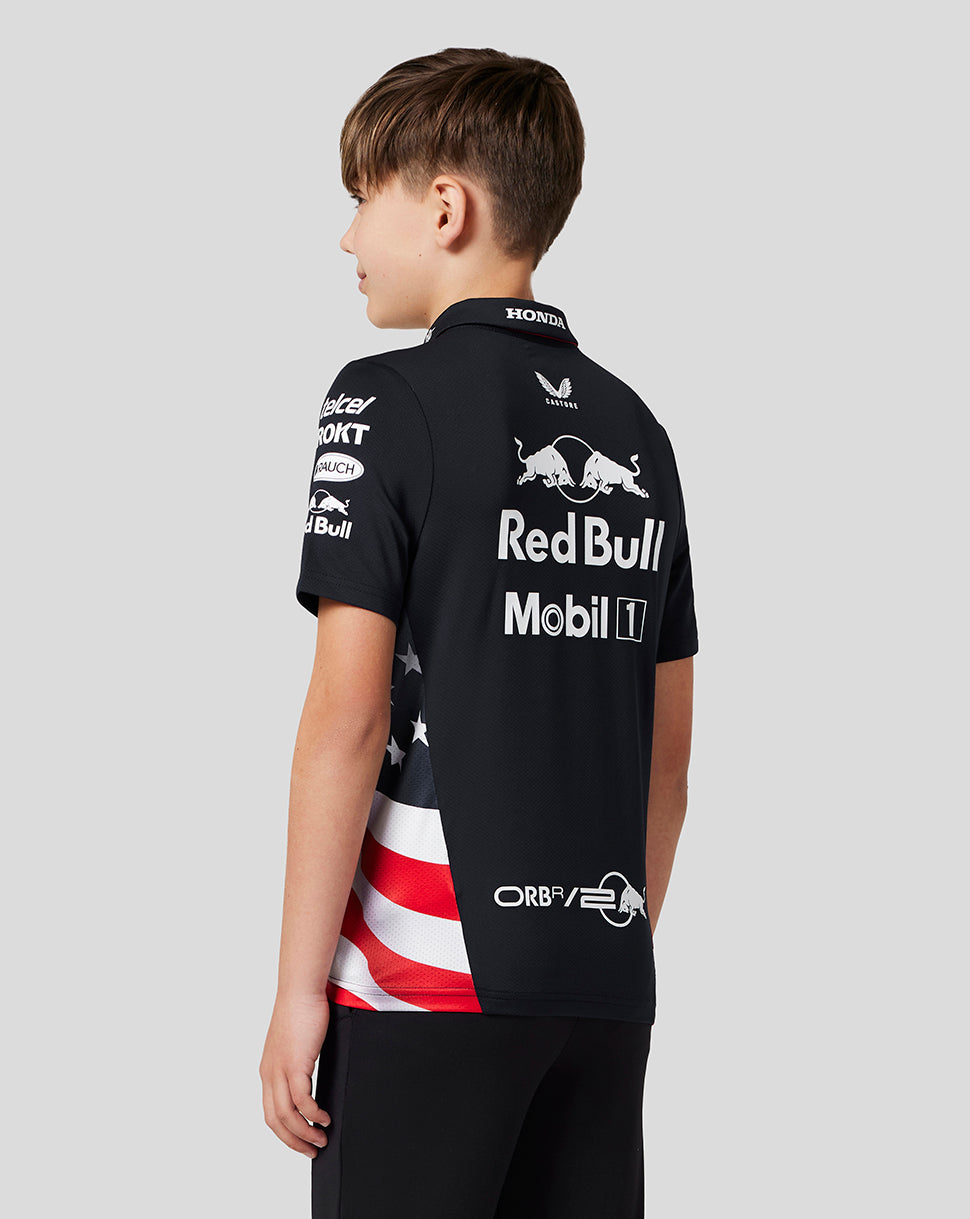 Back view of a young boy wearing a black Oracle Red Bull Racing polo with large white logos on the back and a flag panel on the side.
