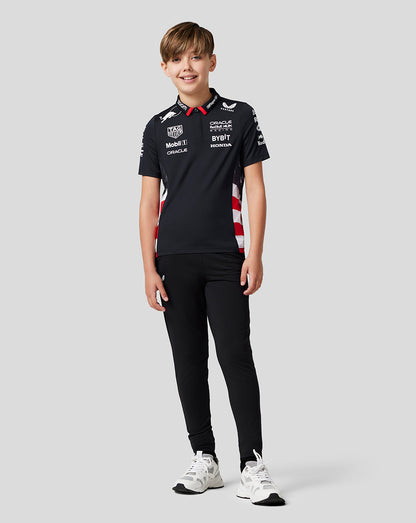 Full body shot of a boy in a Night Sky navy team polo with red and white side panels, black pants and white sneakers.