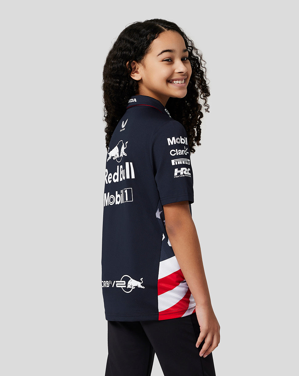 Front profile of a smiling girl wearing a navy Red Bull Racing polo with sponsor logos and red trimmed collar.