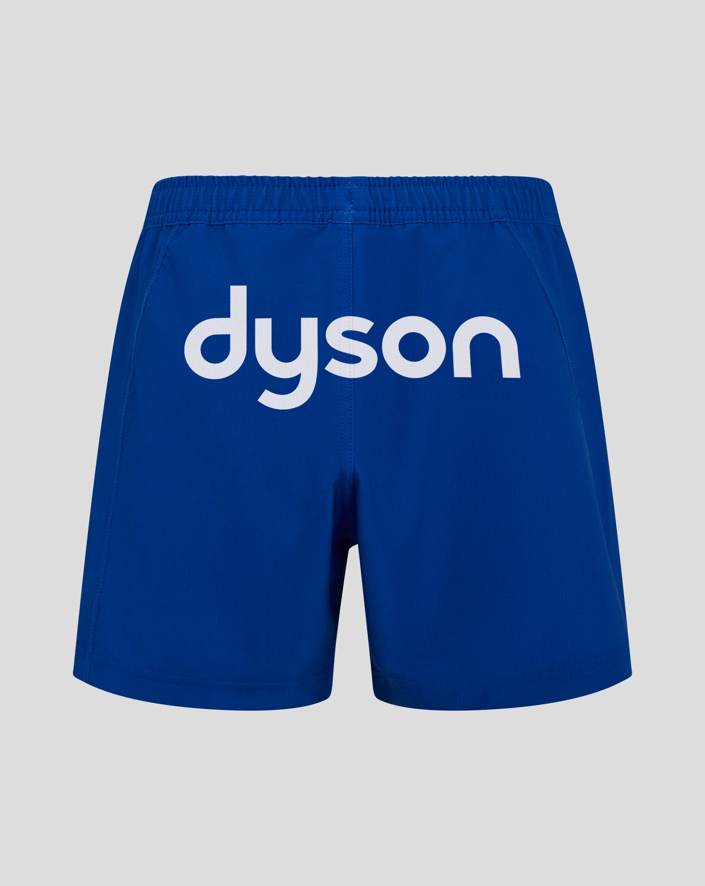Back view of blue Bath Rugby Junior Away Shorts with large white Dyson logo across the seat and an elastic waistband.