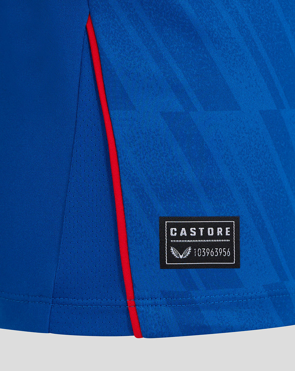 Close-up of blue Rangers Junior home long sleeve shirt showing red piping along the side seam and Castore label patch.