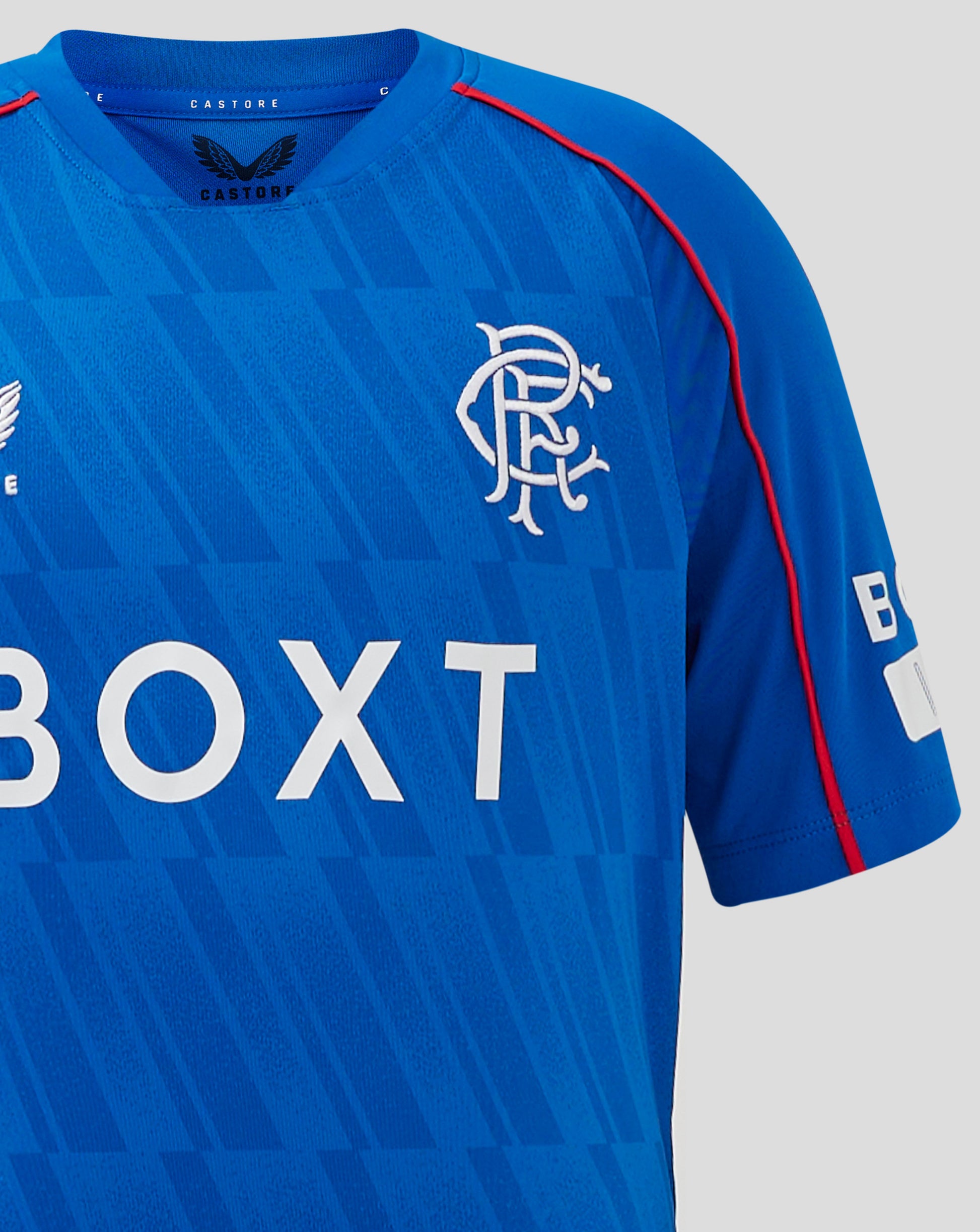 Rangers Junior Home Shirt blue with a geometric front pattern; left chest crest, right chest Castore logo, and sponsor text across the lower front.