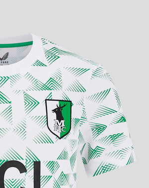 Close-up of Mansfield Junior Away Shirt front showing green chevron print and chest crest with Castore branding.