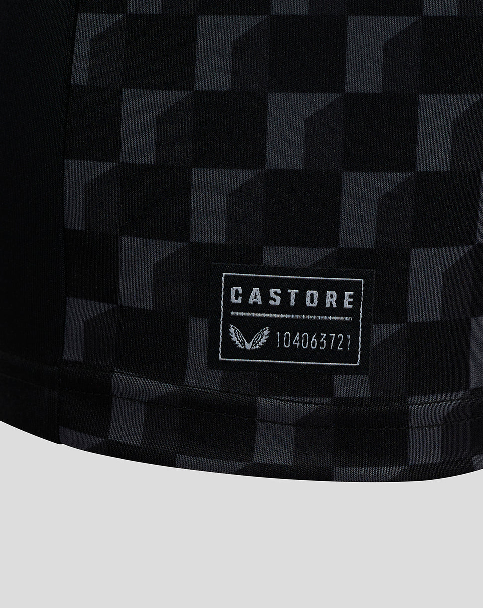 Close-up of Mansfield Junior shirt fabric with a dark checkerboard pattern and Castore label patch