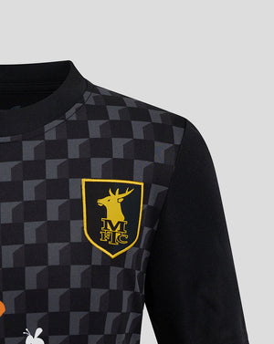 Close-up of Mansfield Junior 24/25 Third Shirt crest on chest with dark checkerboard pattern.