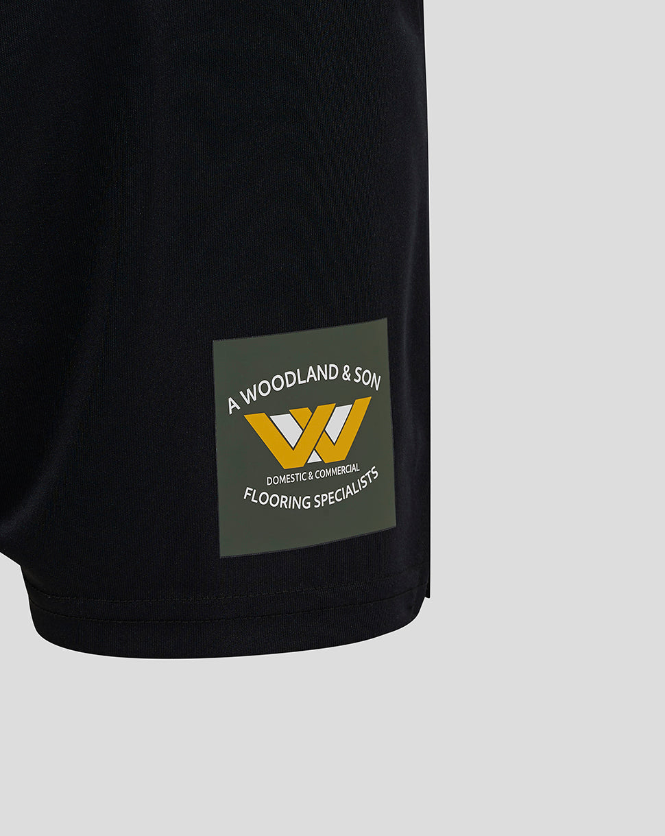 Close-up of the lower left leg of the shorts showing a Woodland & Son logo patch