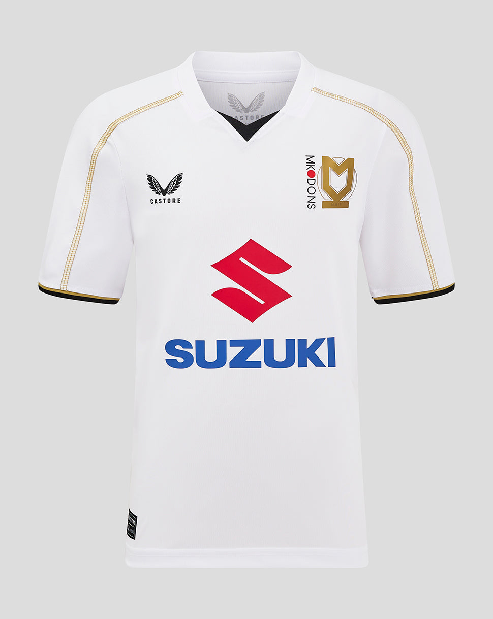 Front view of white MK Dons junior home shirt with Suzuki sponsor and gold piping along the shoulder seams.