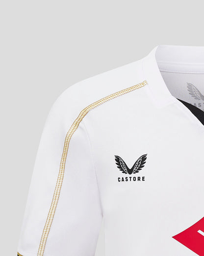 Close up of a white MK Dons junior home shirt showing gold shoulder piping and Castore logo
