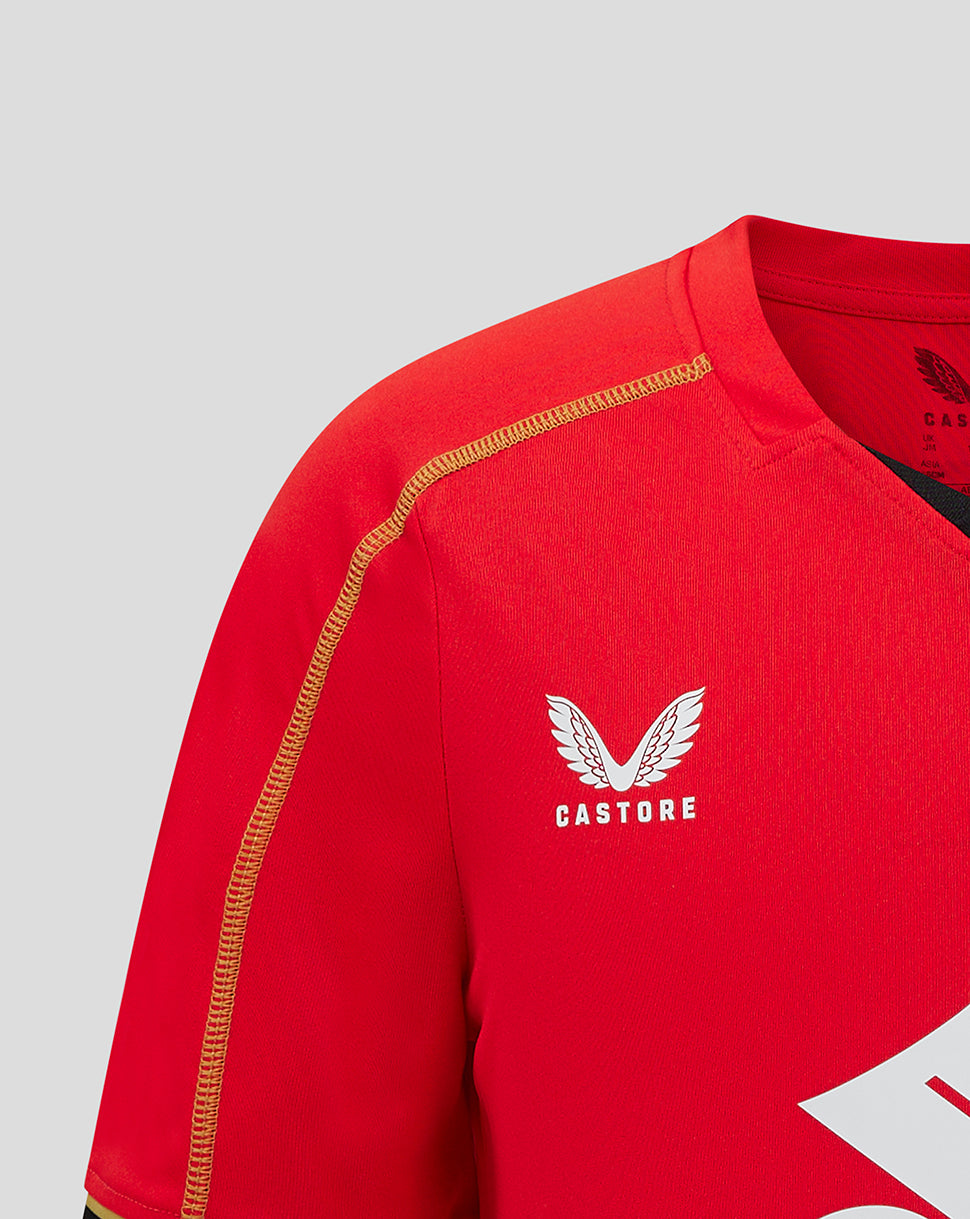 Close up of red Mk Dons jersey showing gold shoulder piping and Castore logo.