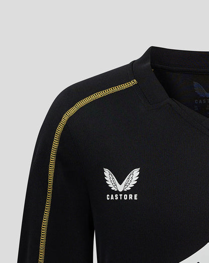 Close-up of black MK DONS training top with gold shoulder piping and white wing crest and CASTORE branding.