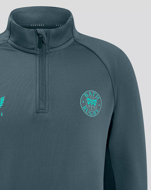 Close up of chest area on teal Bath Rugby top showing Castore logo on the left and Bath Rugby crest on the right