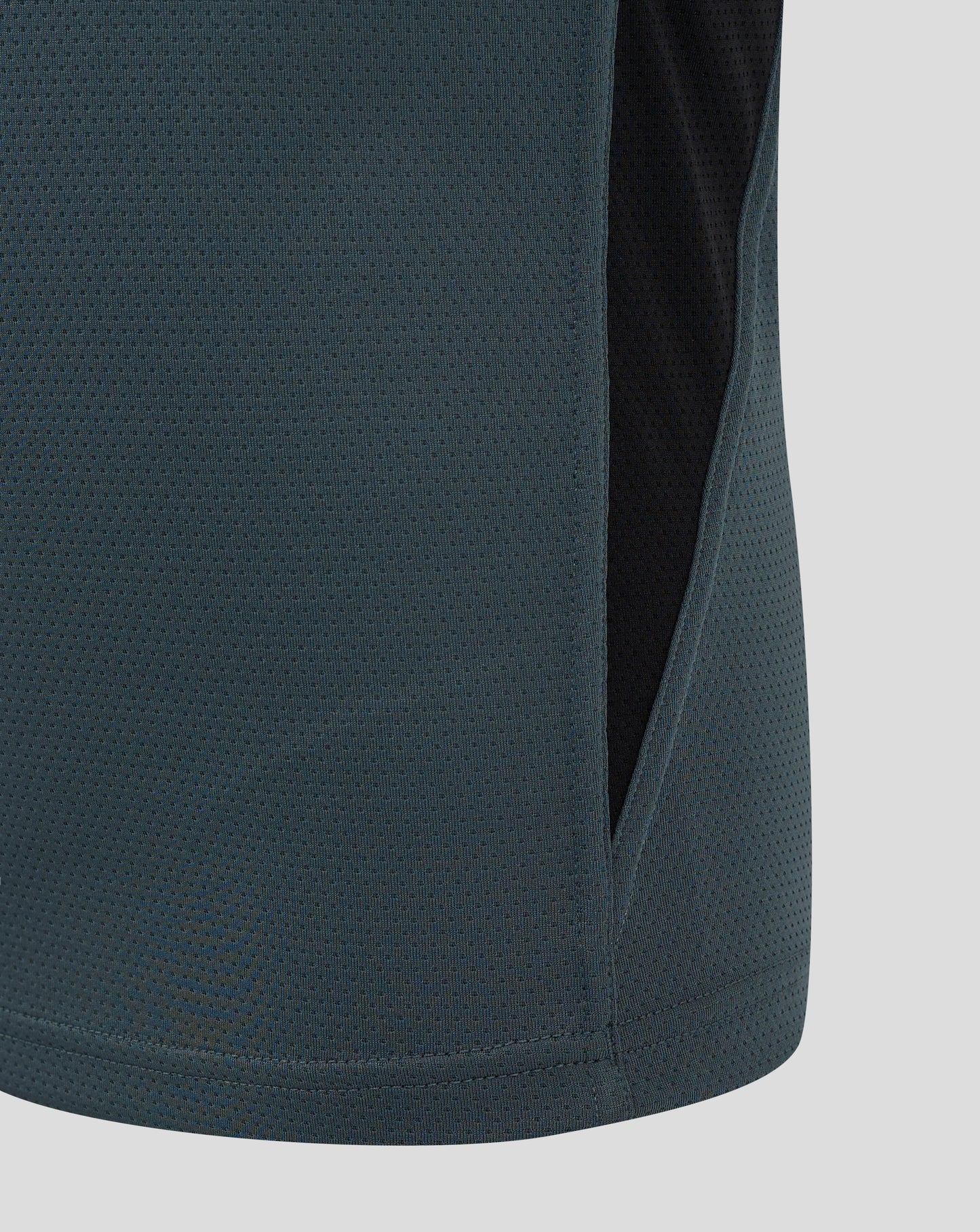 Close up of teal Bath Rugby junior training shirt fabric with a dotted perforated pattern and a side panel seam